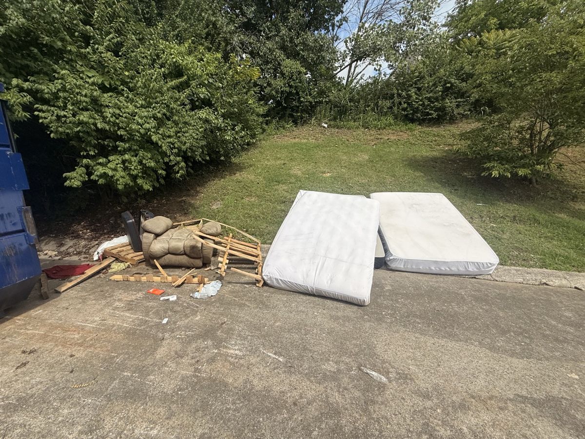 Before: mattresses and broken furniture overflowing beside a dumpster in Middle Tennessee